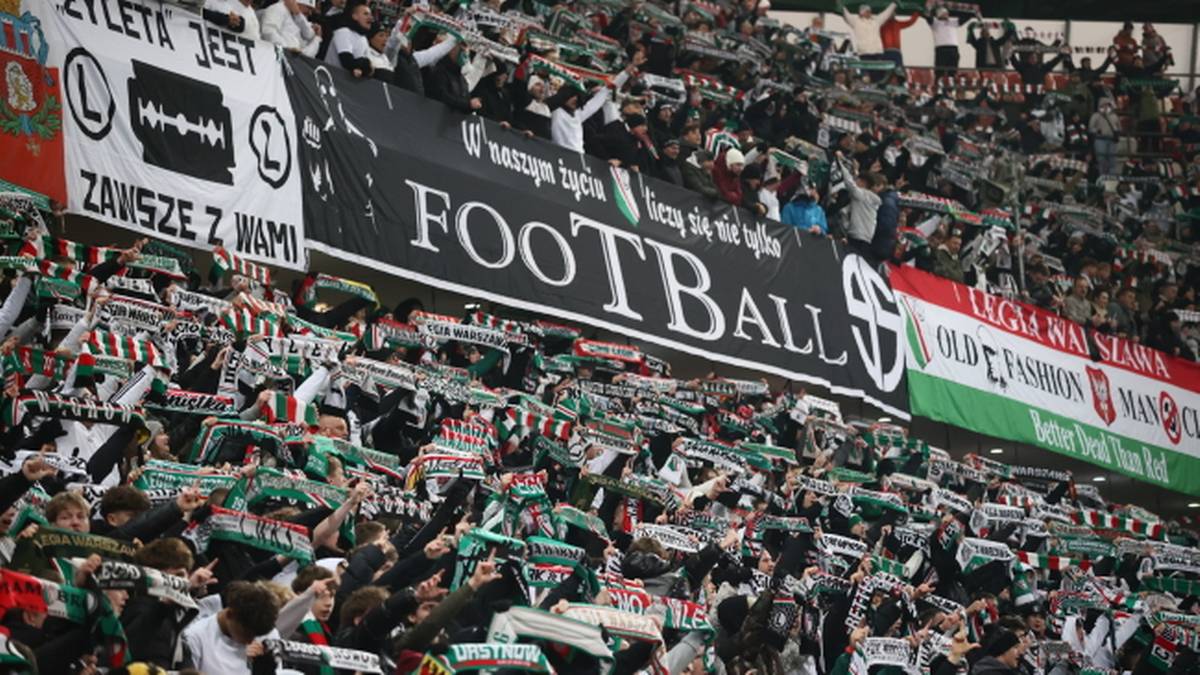 Tłum kibiców Legii Warszawa na trybunach stadionu z transparentami i szalikami