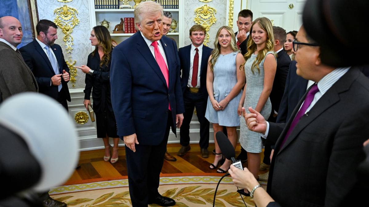 Donald Trump w otoczeniu ludzi, rozmawia z grupą os&oacute;b w oficjalnym pomieszczeniu.