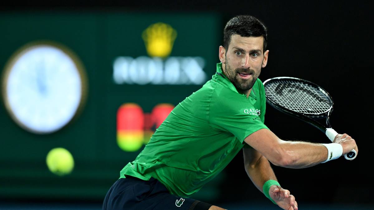 Novak Djoković podczas meczu tenisowego, wykonuje zamach rakietą.