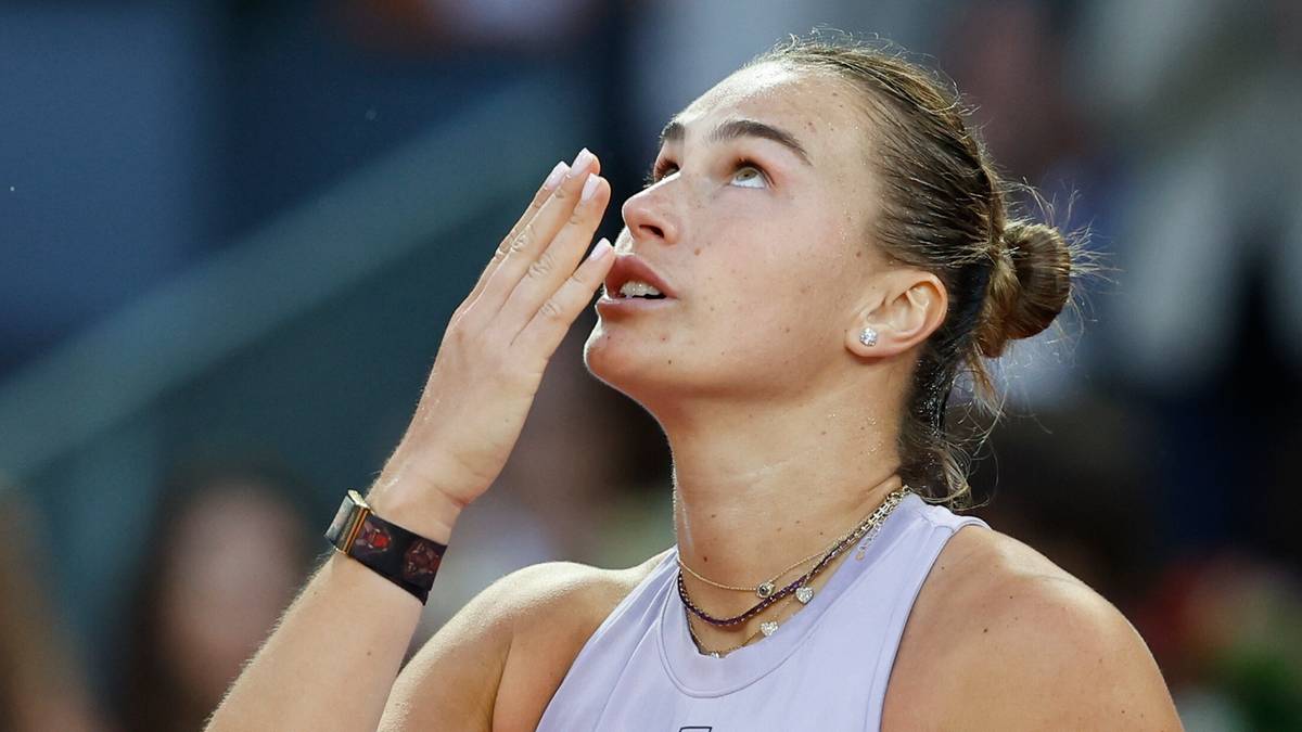 Tenisistka Aryna Sabalenka w pobliżu twarzy unosi dłoń, patrząc w g&oacute;rę.