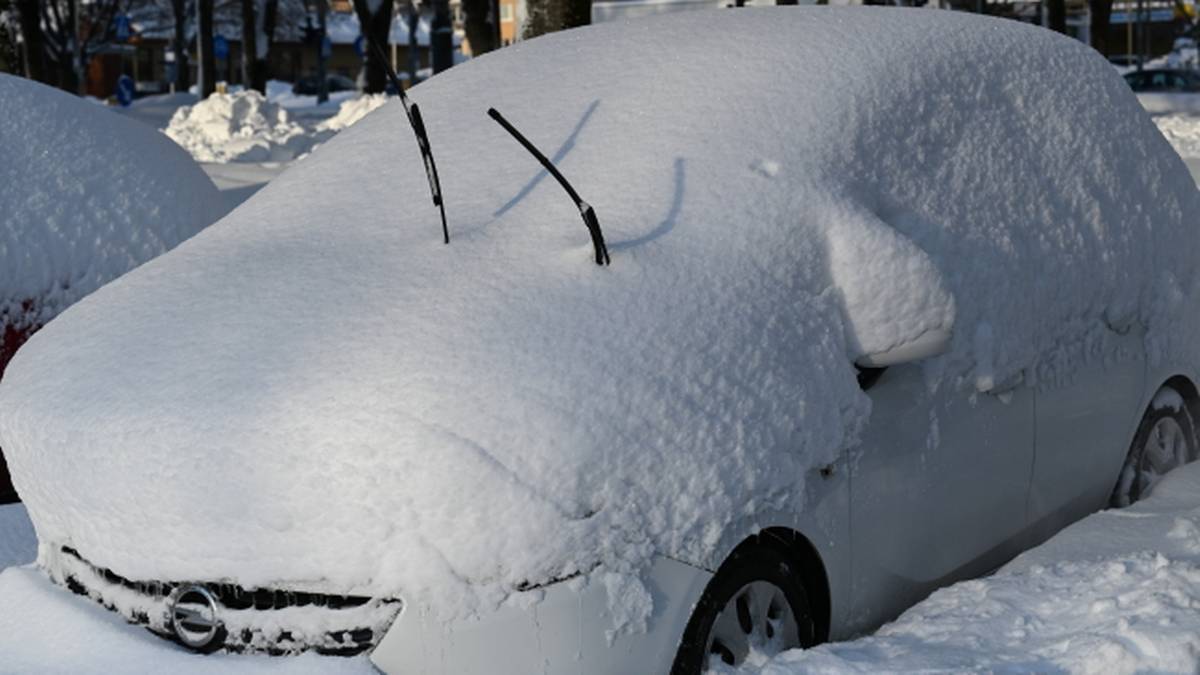 Samoch&oacute;d całkowicie pokryty grubą warstwą śniegu, z widocznymi wycieraczkami sterczącymi ze śniegu.