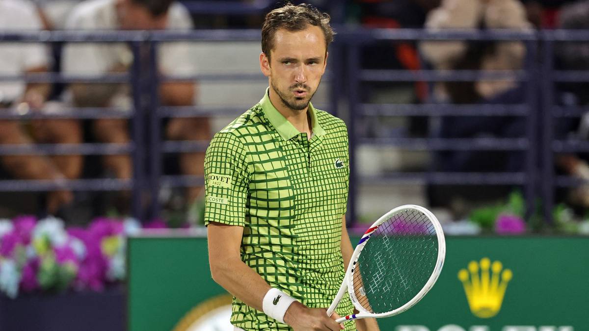 Tenisista Daniił Miedwiediew z rakietą, w zielonej koszulce, z poważną miną.