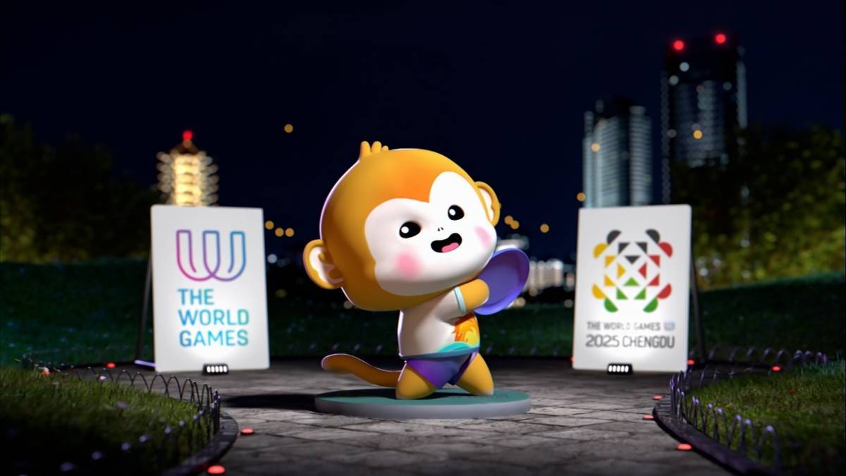 Maskotka The World Games 2025, małpka o imieniu Miki, w krótkich spodenkach, trzymająca fioletową dyskę, stoi między dwoma planszami z logotypami igrzysk. W tle nocny krajobraz miasta z oświetlonymi budynkami.