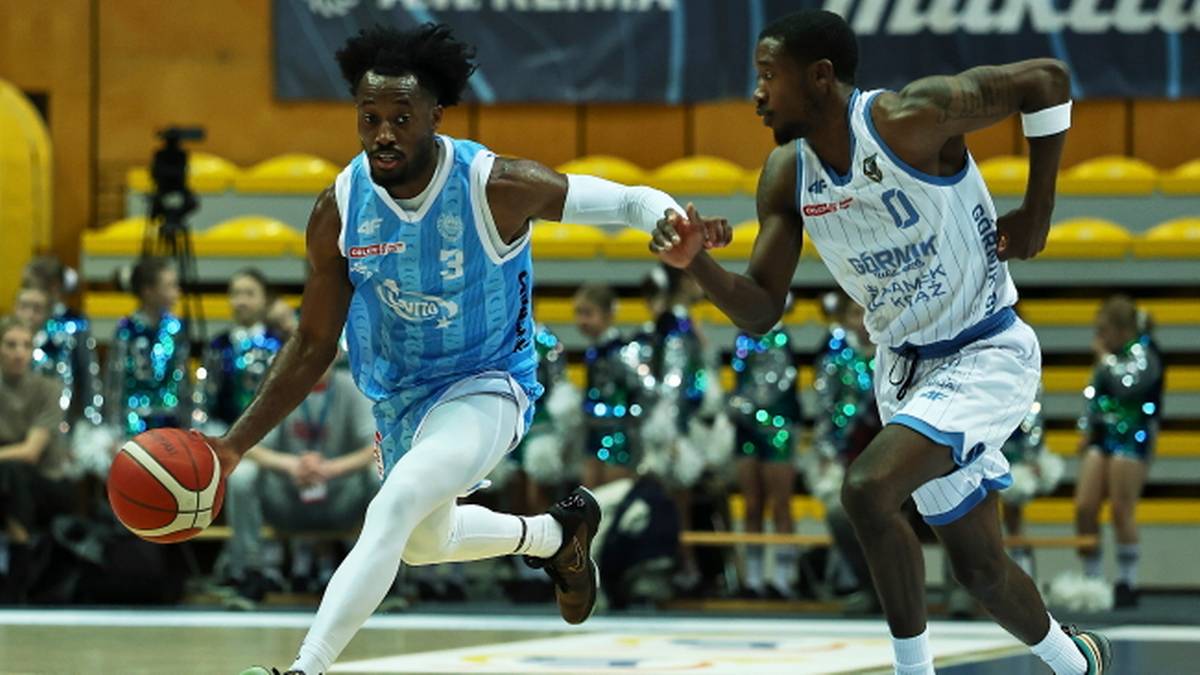 Dwóch koszykarzy w strojach sportowych podczas meczu, jeden z nich prowadzi piłkę.