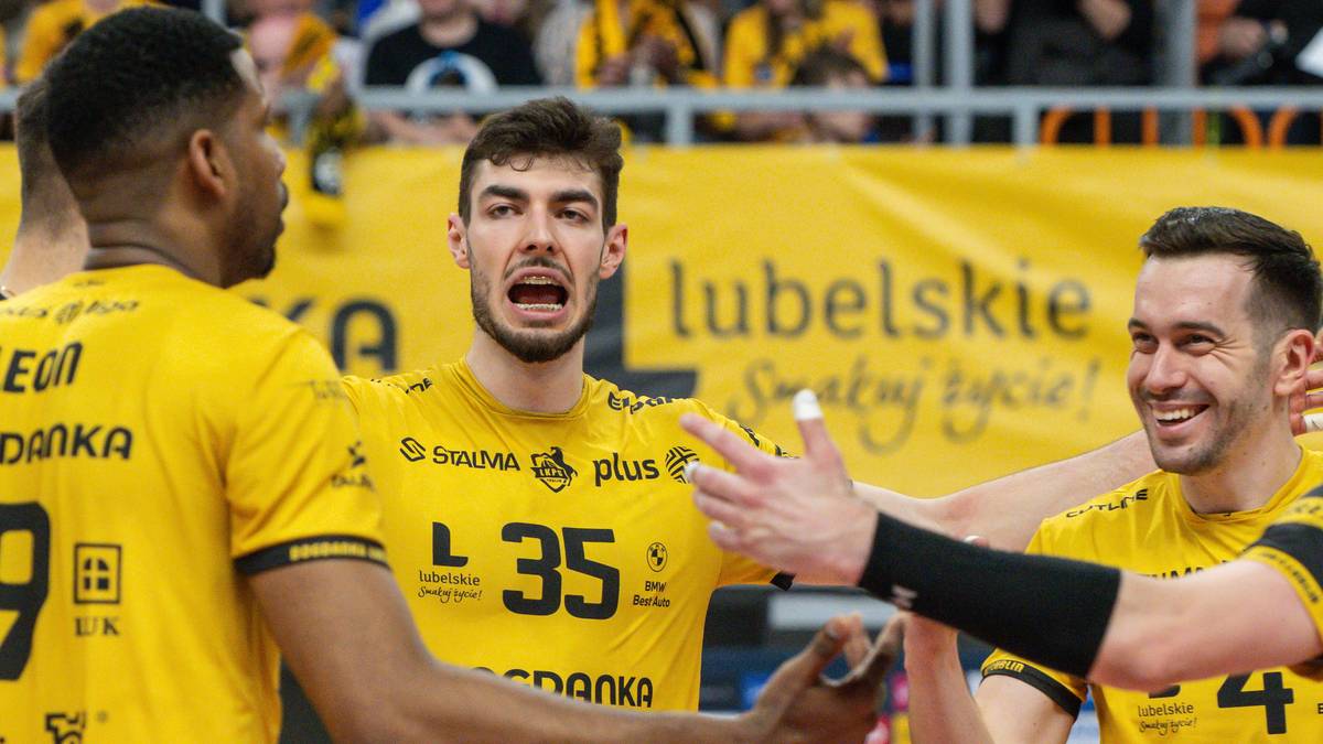 Trzech siatkarzy w żółtych koszulkach, z numerami 35 i 29, cieszy się ze zwycięstwa, bijąc się po rękach i śmiejąc. Jeden z nich otwiera usta w okrzyku radości.