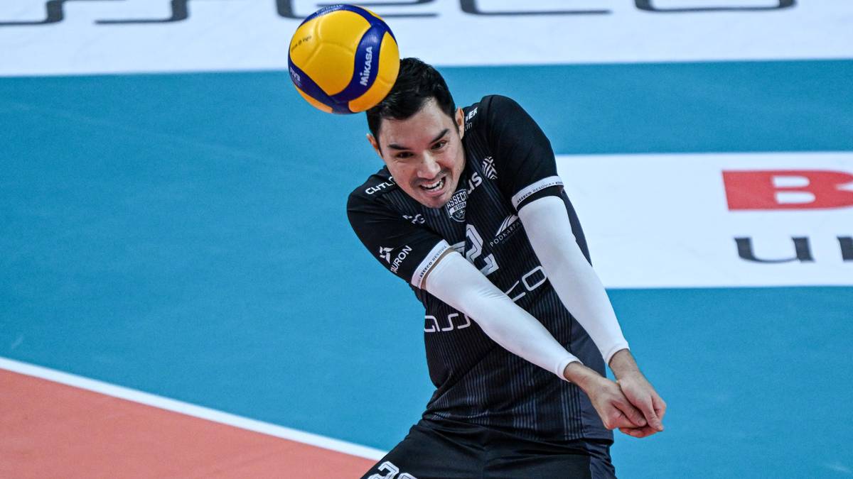 Siatkarz w czarnej koszulce z numerem 22 na boisku z piłką nad głową