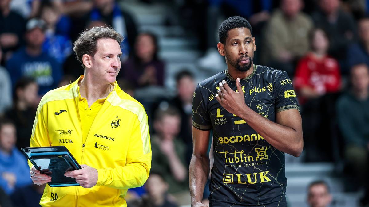 Dw&oacute;ch siatkarzy na boisku siatkarskim, jeden w ż&oacute;łtej kurtce, drugi w czarnej koszulce z logotypami.