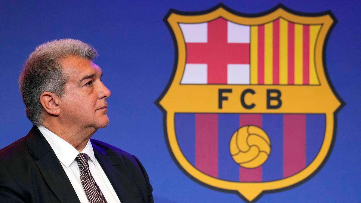 Portret mężczyzny w garniturze i krawacie, patrzącego w bok, z logo FC Barcelona w tle.