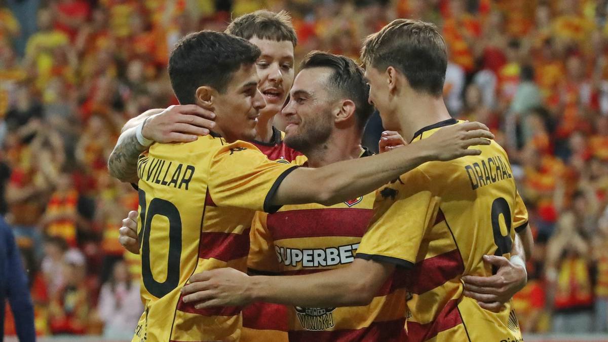 Czterech piłkarzy w żółtych koszulkach świętuje razem, obejmując się nawzajem. Na koszulkach widoczne są numery i nazwiska zawodników.