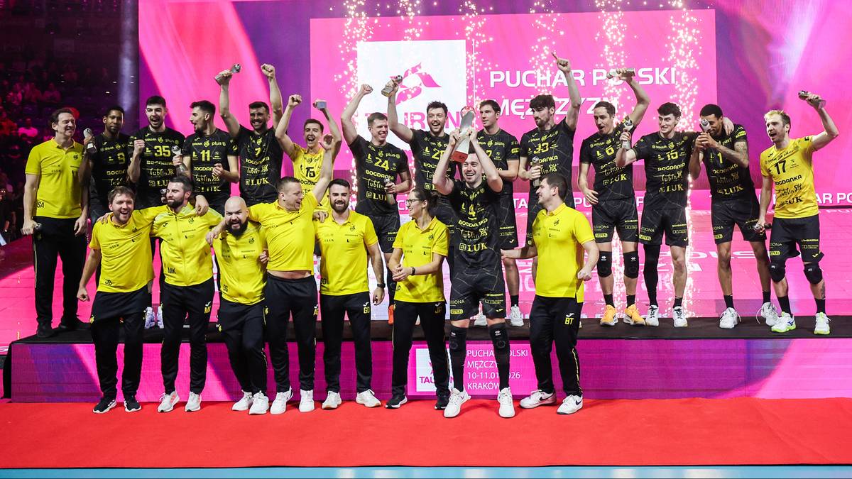 Drużyna siatkarzy Bogdanki LUK Lublin świętująca zwycięstwo na podium z fajerwerkami w tle.