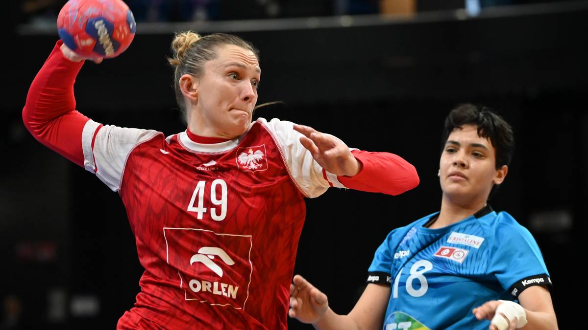 Zawodniczka piłki ręcznej w czerwonej koszulce z numerem 49 rzuca piłkę, obok niej zawodniczka w niebieskiej koszulce z numerem 18.