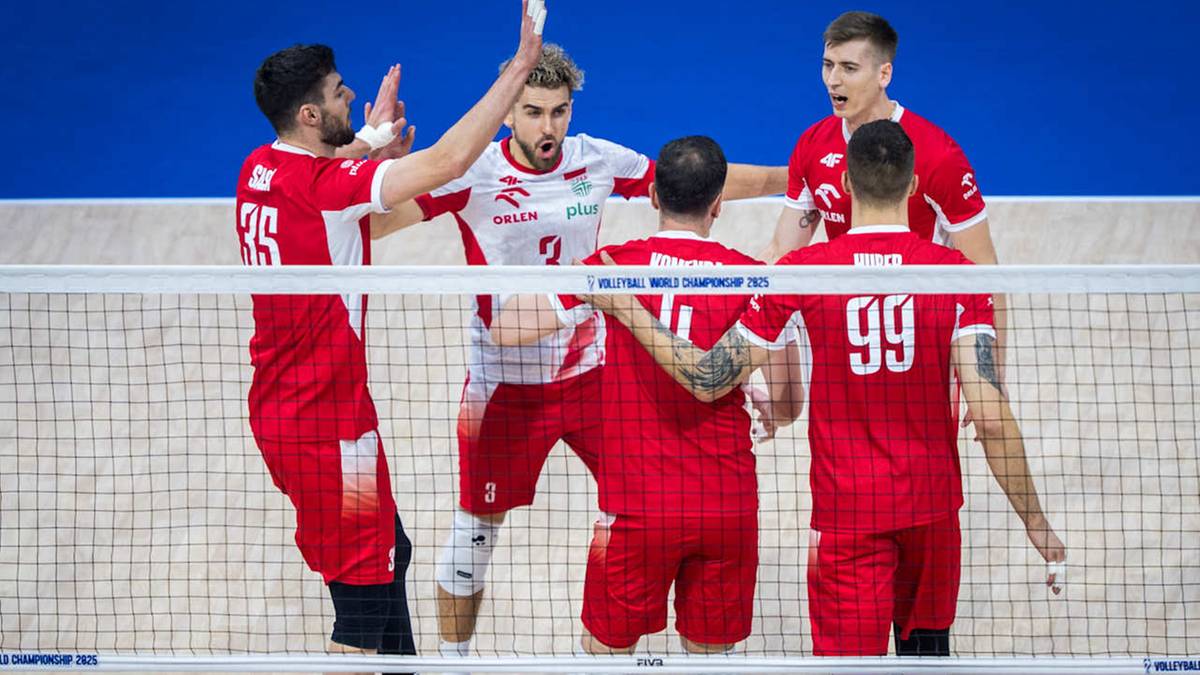 Pięciu mężczyzn w czerwonych strojach siatkarskich świętuje zwycięstwo na boisku, z rękami w górze i z uśmiechami na twarzach.