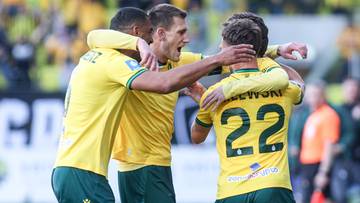 Trzech piłkarzy w ż&oacute;łtych koszulkach celebruje zdobycie bramki, obejmując się nawzajem.