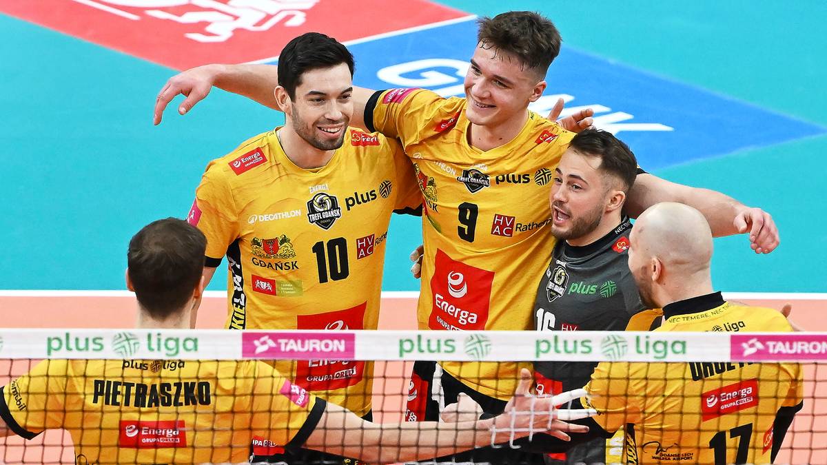 Trzech siatkarzy Trefla Gdańsk w żółtych strojach cieszy się ze zwycięstwa, obejmując się nawzajem.