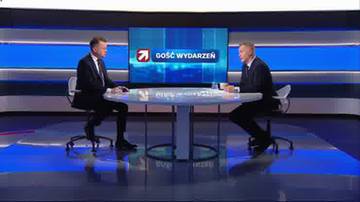 Dw&oacute;ch mężczyzn siedzi naprzeciwko siebie przy okrągłym stole w studiu telewizyjnym. Na ekranie za nimi widnieje logo "Gość Wydarzeń".