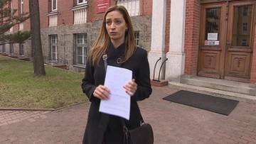 Kobieta trzymająca dokumenty przed budynkiem