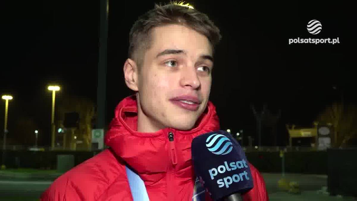 Młody mężczyzna w czerwonej kurtce odpowiada na pytanie, trzymając mikrofon Polsat Sport.