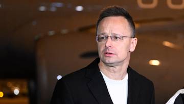 Szef MSZ Węgier Peter Szijjarto stoi przed mikrofonami, po jego prawej stronie widać kilku mężczyzn.