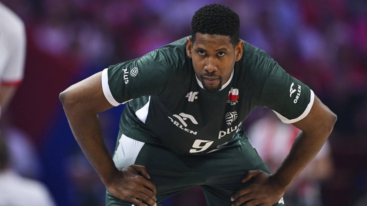 Siatkarz Leon, w zielonej koszulce reprezentacji Polski, z rękami opartymi na biodrach, skupiony podczas meczu.