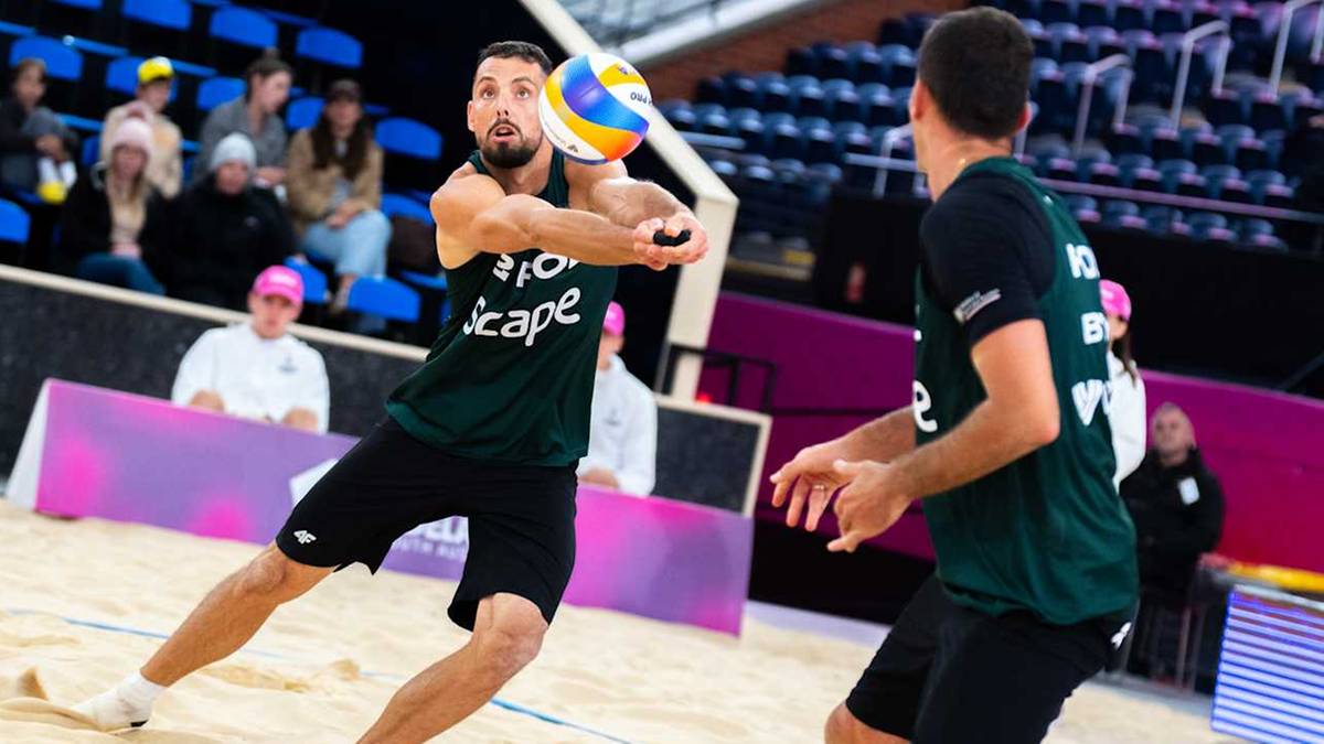 Siatkarz plażowy w zielonej koszulce wykonuje zagranie oburącz