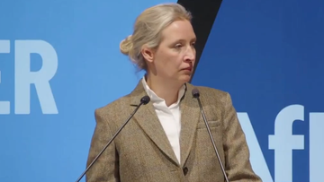 Kobieta w garniturze przemawia za m&oacute;wnicą.