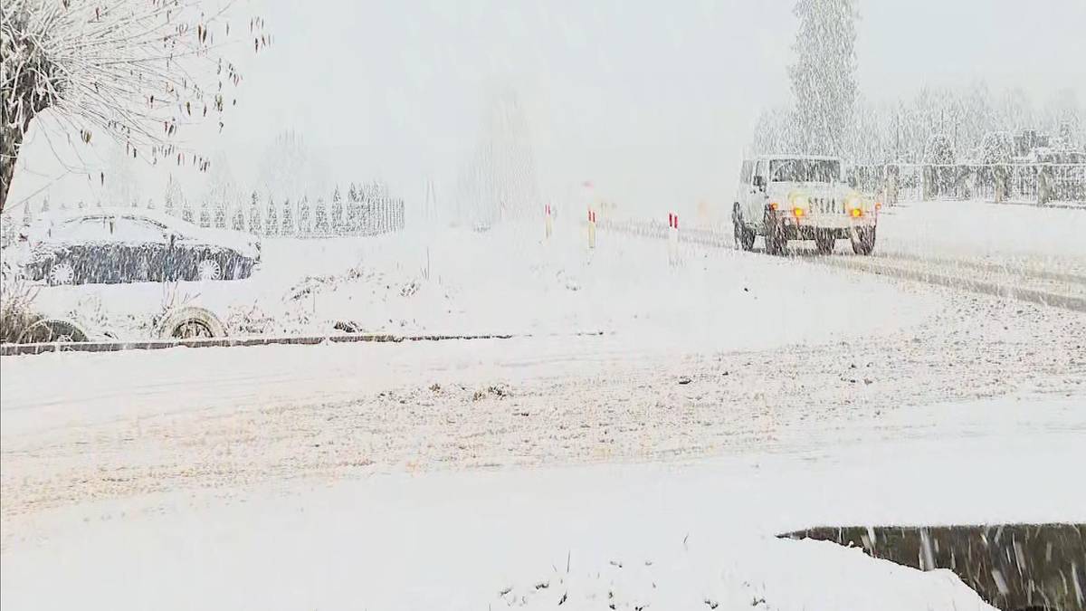 Droga pokryta śniegiem z samochodami w korku podczas intensywnych opadów.