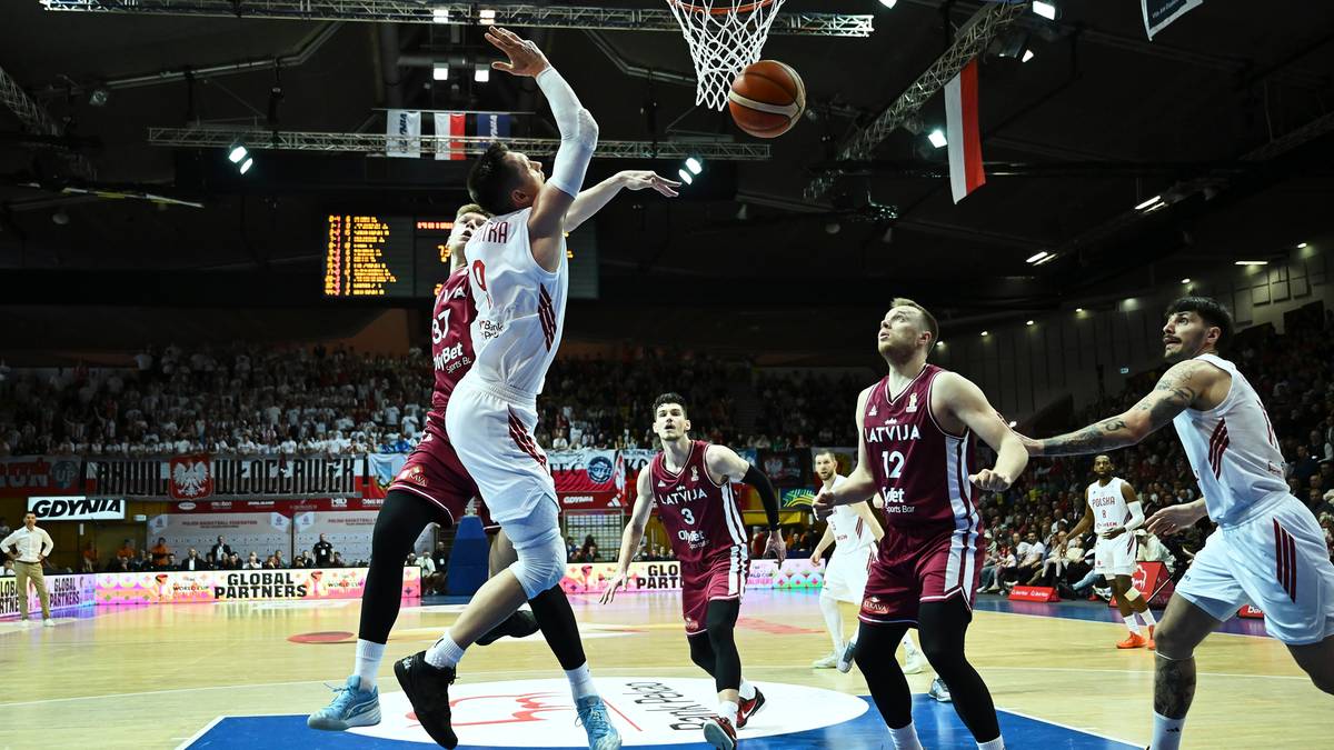 Zawodnicy drużyny koszykarskiej walczący o piłkę pod koszem podczas meczu.