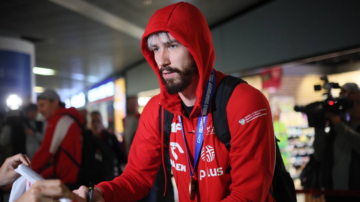 Tomasz Fornal w czerwonej bluzie z kapturem, z plecakiem na ramieniu, ubrany w strój sportowy.