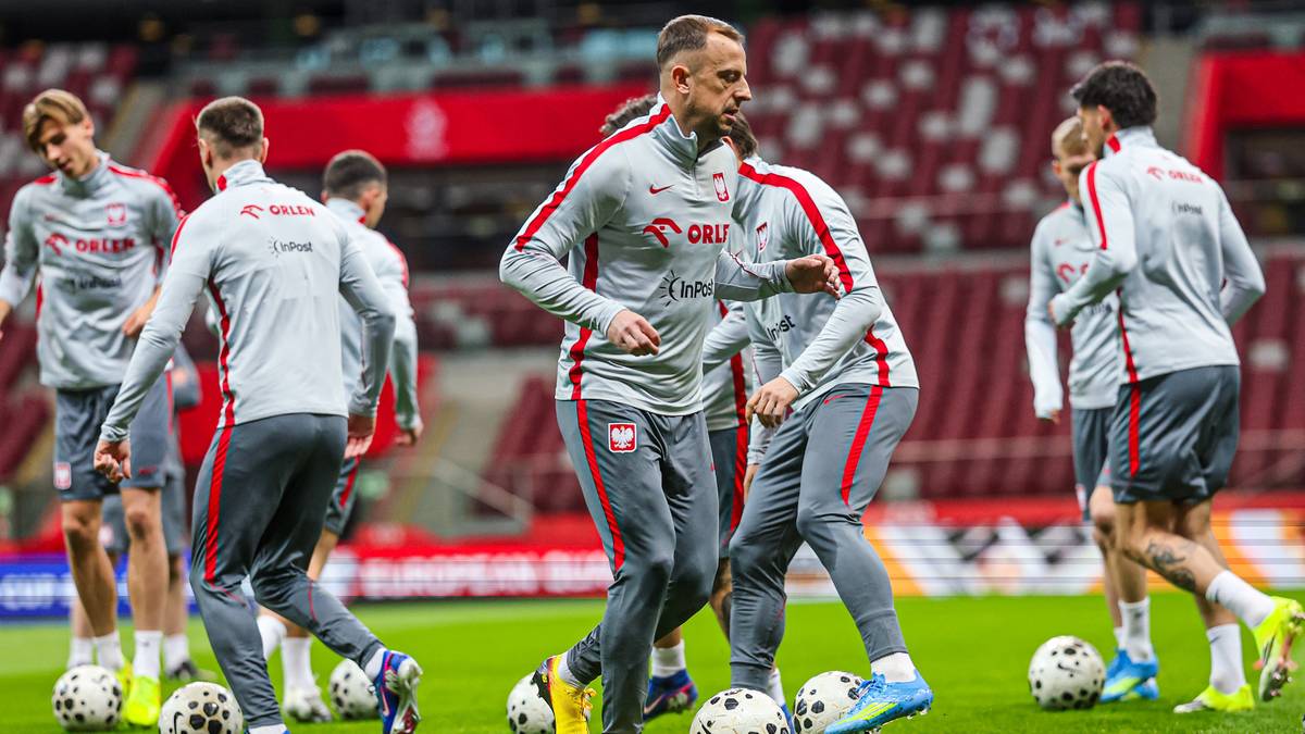 Piłkarze reprezentacji Polski w strojach treningowych na boisku, przygotowujący się do meczu.