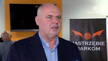 Artur Popko w garniturze i koszuli w kratę wypowiada się podczas wywiadu