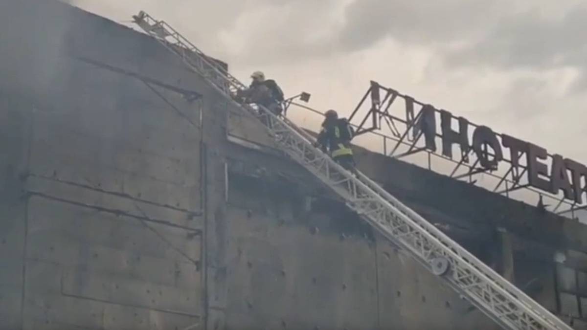 Strażacy na drabinie przy dachu centrum handlowego podczas akcji gaśniczej.