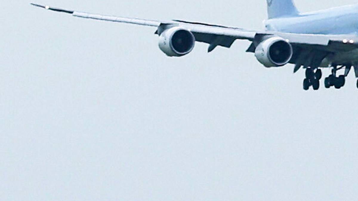 Fragment samolotu pasażerskiego z widocznymi silnikami i podwoziem, zbliżający się do lądowania.