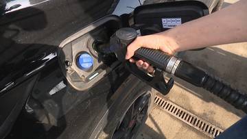 Ręka trzymająca pistolet dystrybutora paliwa wlewa paliwo do baku samochodu.