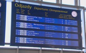 Duża tablica informacyjna na dworcu kolejowym z listą odjazd&oacute;w pociąg&oacute;w, z widocznymi op&oacute;źnieniami.