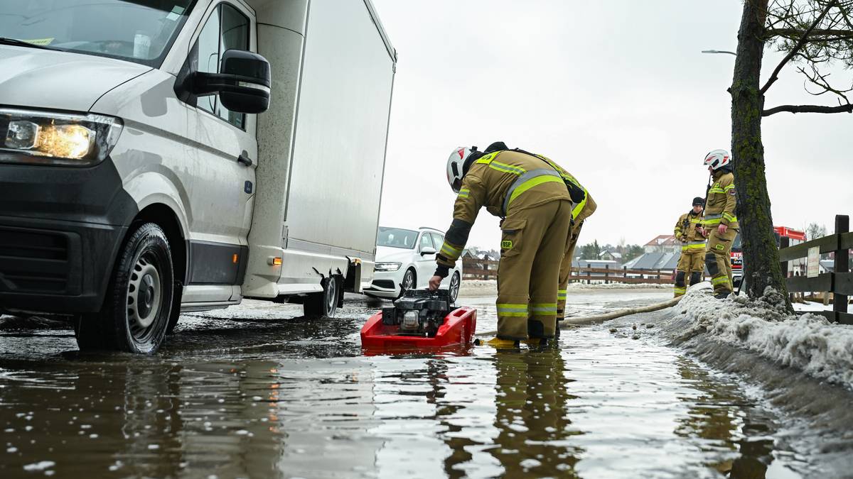 Strażacy wypompowują wodę z zalanej drogi.