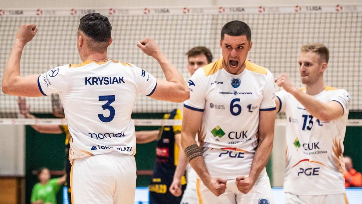 Siatkarze w białych strojach świętują zdobyty punkt, z widocznymi numerami na koszulkach.