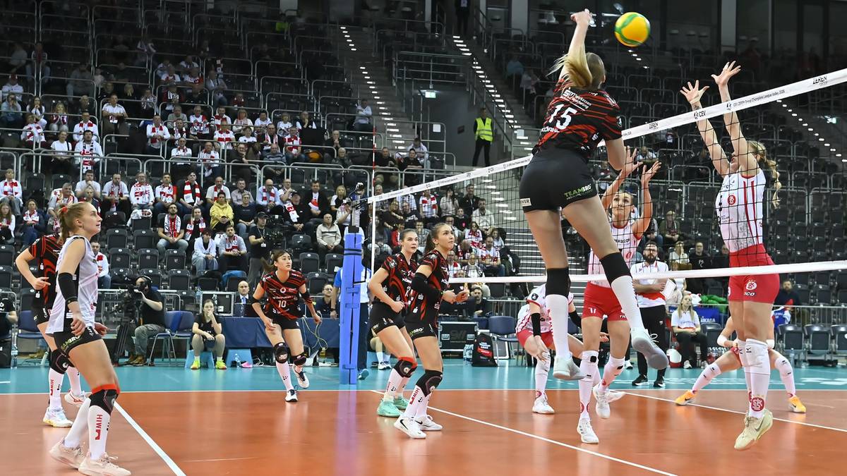 Siatkarka zagrywa piłkę podczas meczu, przeciwniczka próbuje ją odbić.