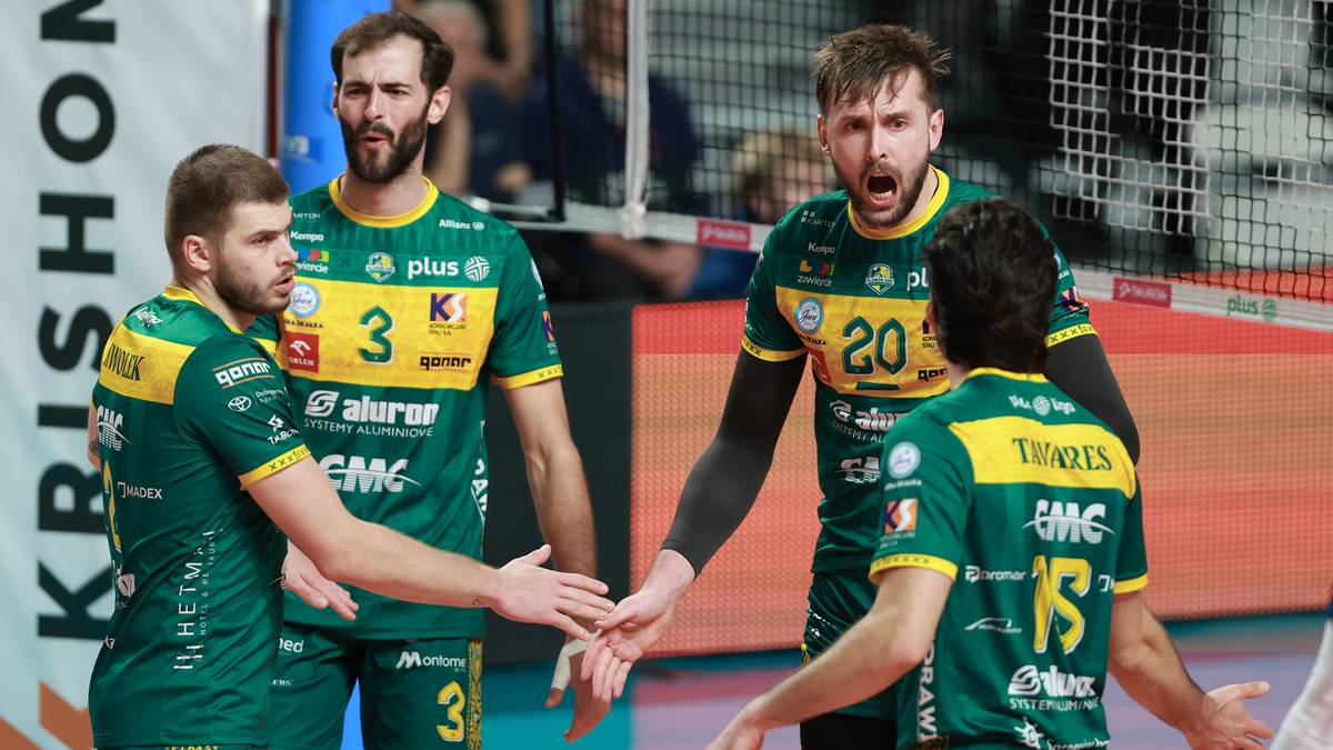 Czterech siatkarzy w zielonych strojach z ż&oacute;łtymi elementami, patrzących na siebie i gestykulujących podczas meczu.