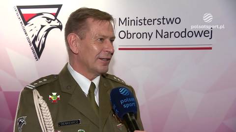 Mężczyzna w mundurze wojskowym, z przypinką z orłem, mówi do mikrofonu z logo "Polsatsport". W tle widoczne logo Ministerstwa Obrony Narodowej.