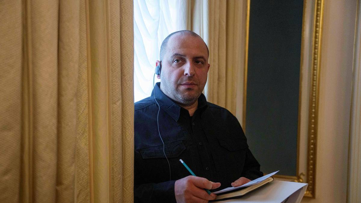 Mężczyzna w czarnej koszuli i słuchawkach trzyma notatnik i ołówek.