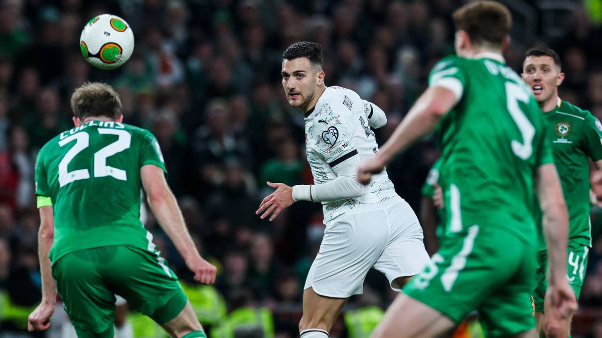 Piłkarze rywalizują o piłkę na boisku podczas meczu.