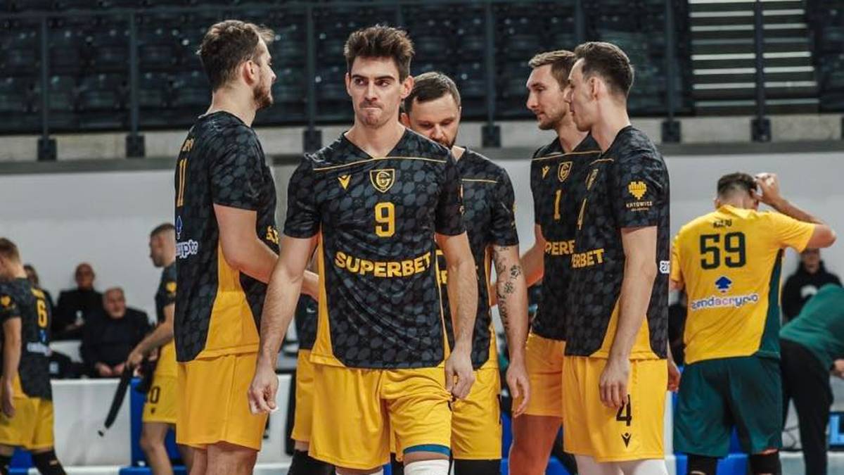 Grupa siatkarzy w żółto-czarnych strojach na boisku, dwóch z nich stoi na pierwszym planie.