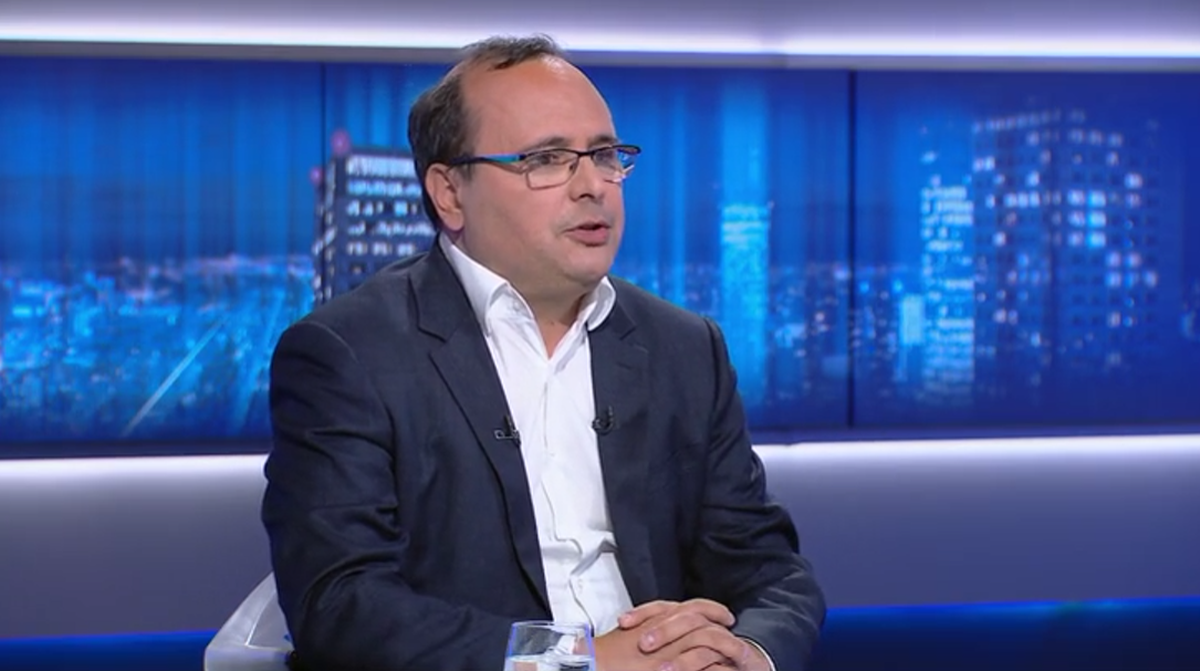 Mężczyzna w okularach siedzi w studiu telewizyjnym