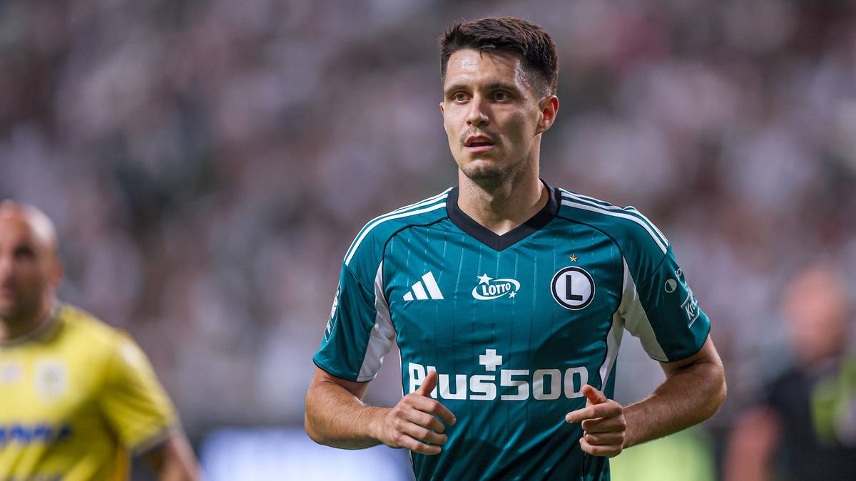 Piłkarz w zielonej koszulce z logo Plus500 biegnie po boisku