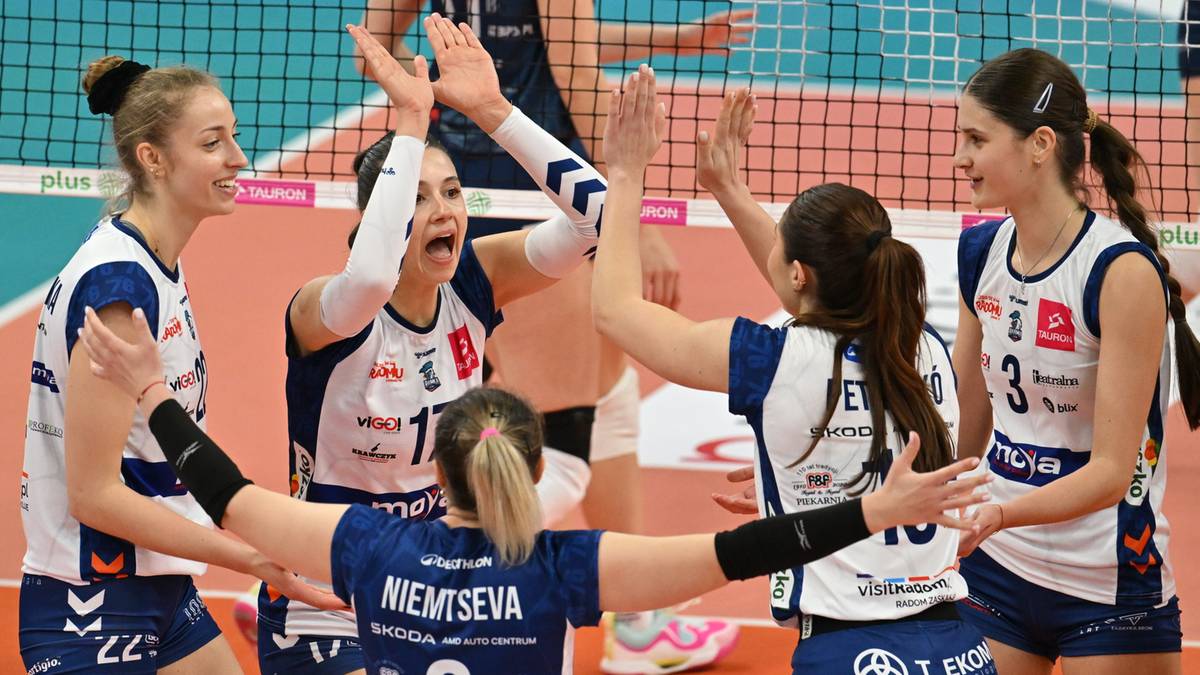 Grupa siatkarek świętuje zdobyty punkt, przybijając sobie piątki.