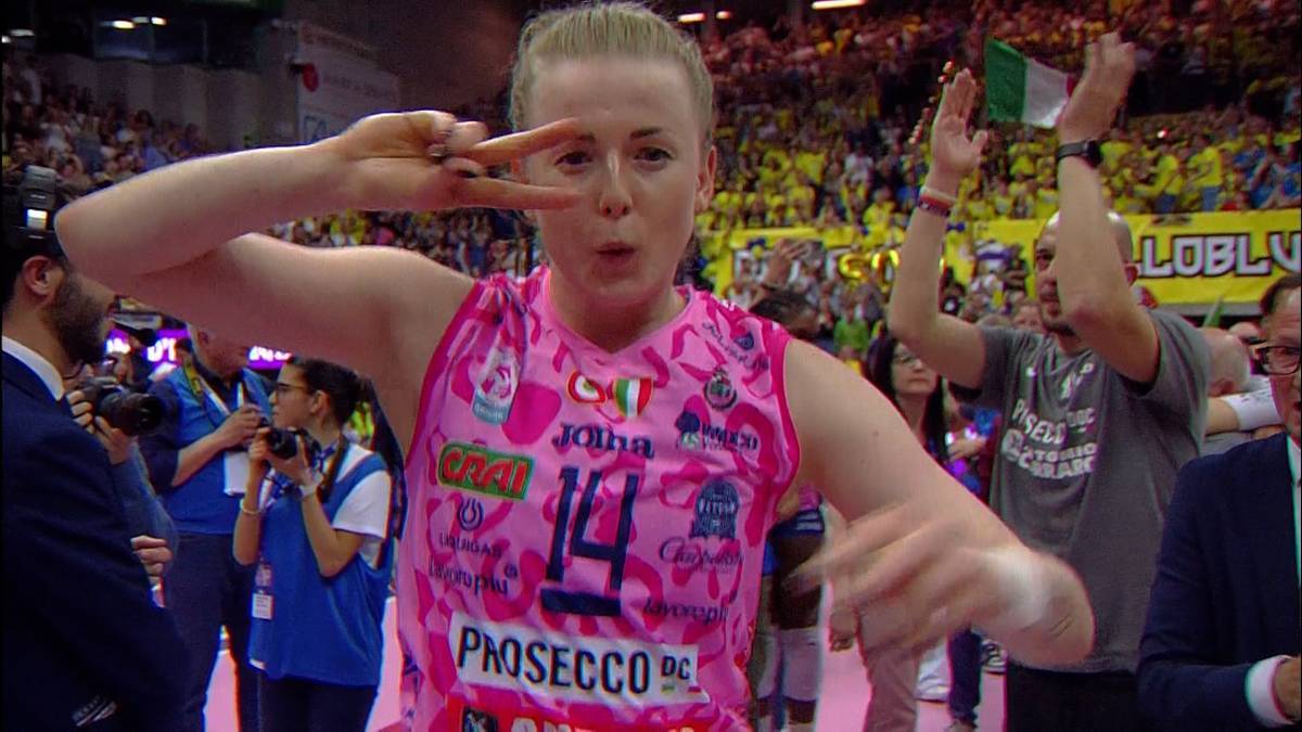 Siatkarka w różowej koszulce z numerem 14 pokazuje znak zwycięstwa palcami.