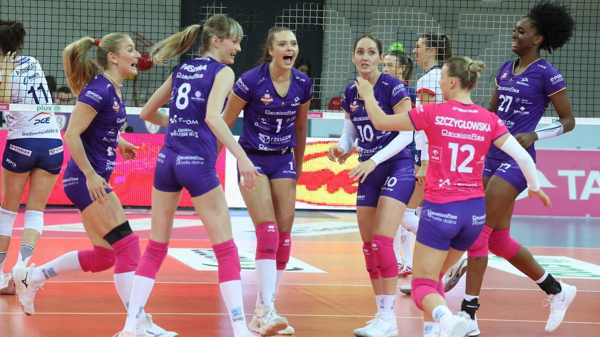Siatkarki w fioletowych strojach świętują na boisku, jedna z nich ma r&oacute;żowy str&oacute;j.