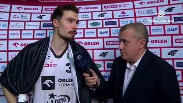 Młody koszykarz w stroju sportowym udziela wywiadu dziennikarzowi na tle ściany z logo "Orlen".