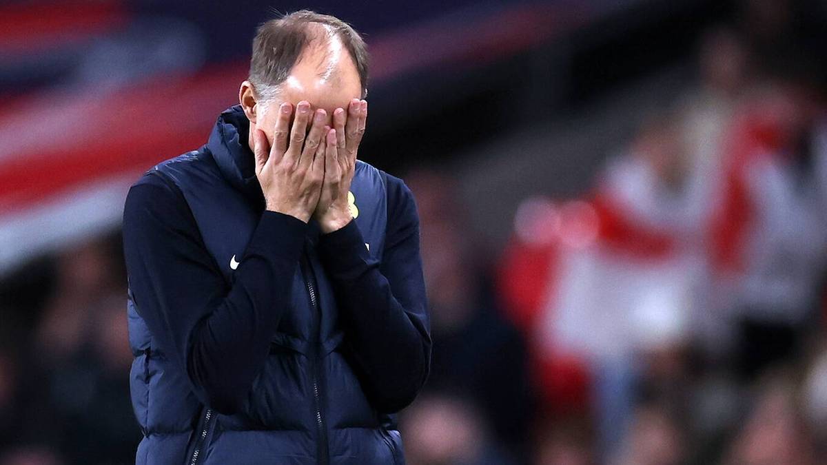 Mężczyzna zakrywający twarz dłońmi na tle stadionu