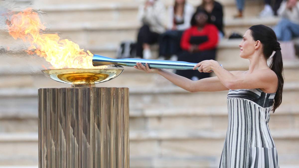 Kobieta trzyma płonący znicz olimpijski.